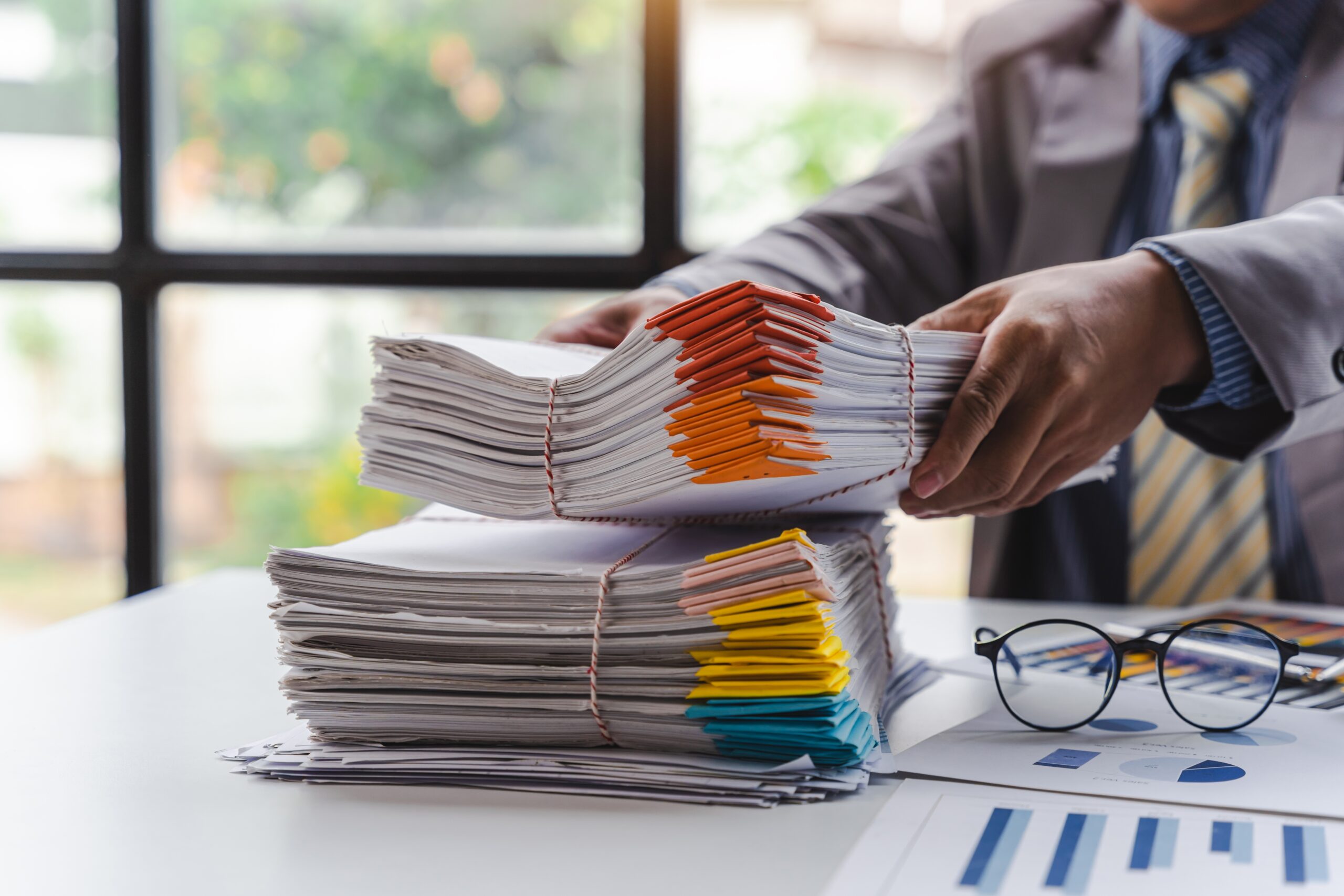 Stack,Of,Documents,,Pile,Of,Papers,On,Office,Desk,Employee's Person filing and organizing documents